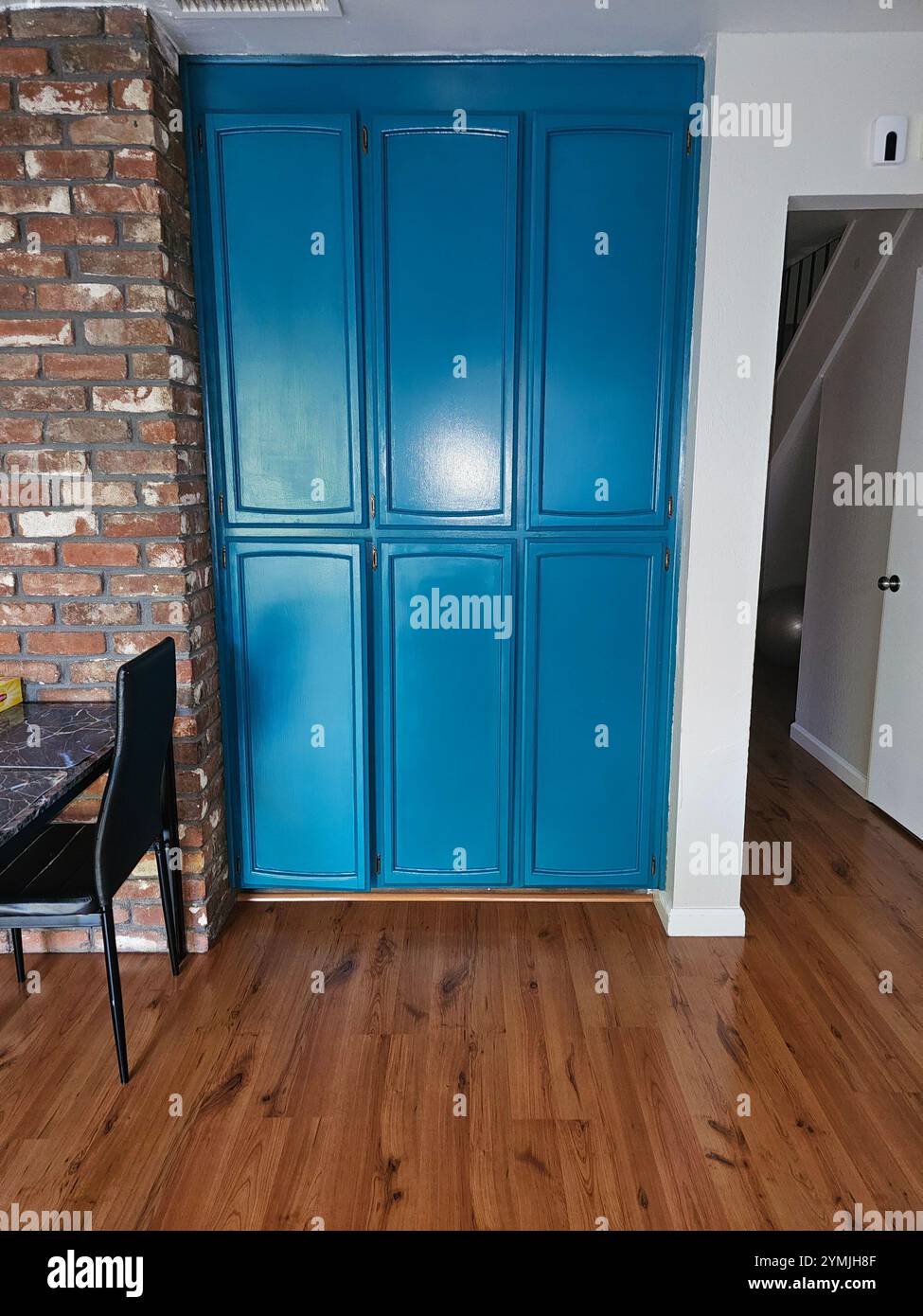 Interni moderni con un vivace armadio turchese, accenti murali in mattoni e pavimento in legno. Perfetto per i temi dell'interior design e dell'arredamento. - Immagine stock catturata con smartphone