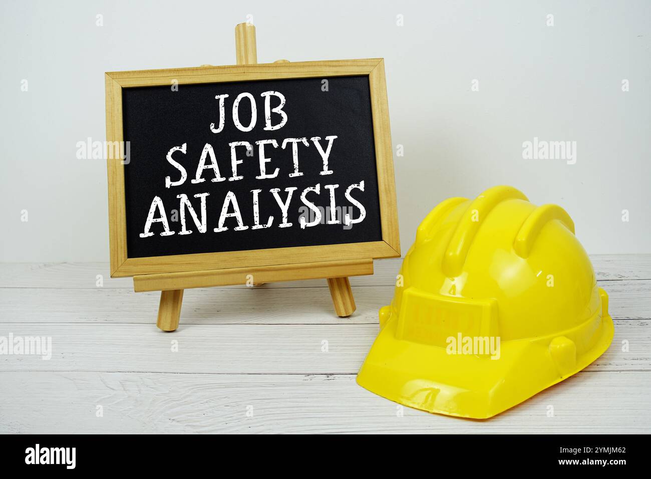 Testo dell'analisi della sicurezza sul lavoro su lavagna con elmetto di sicurezza su sfondo in legno Foto Stock