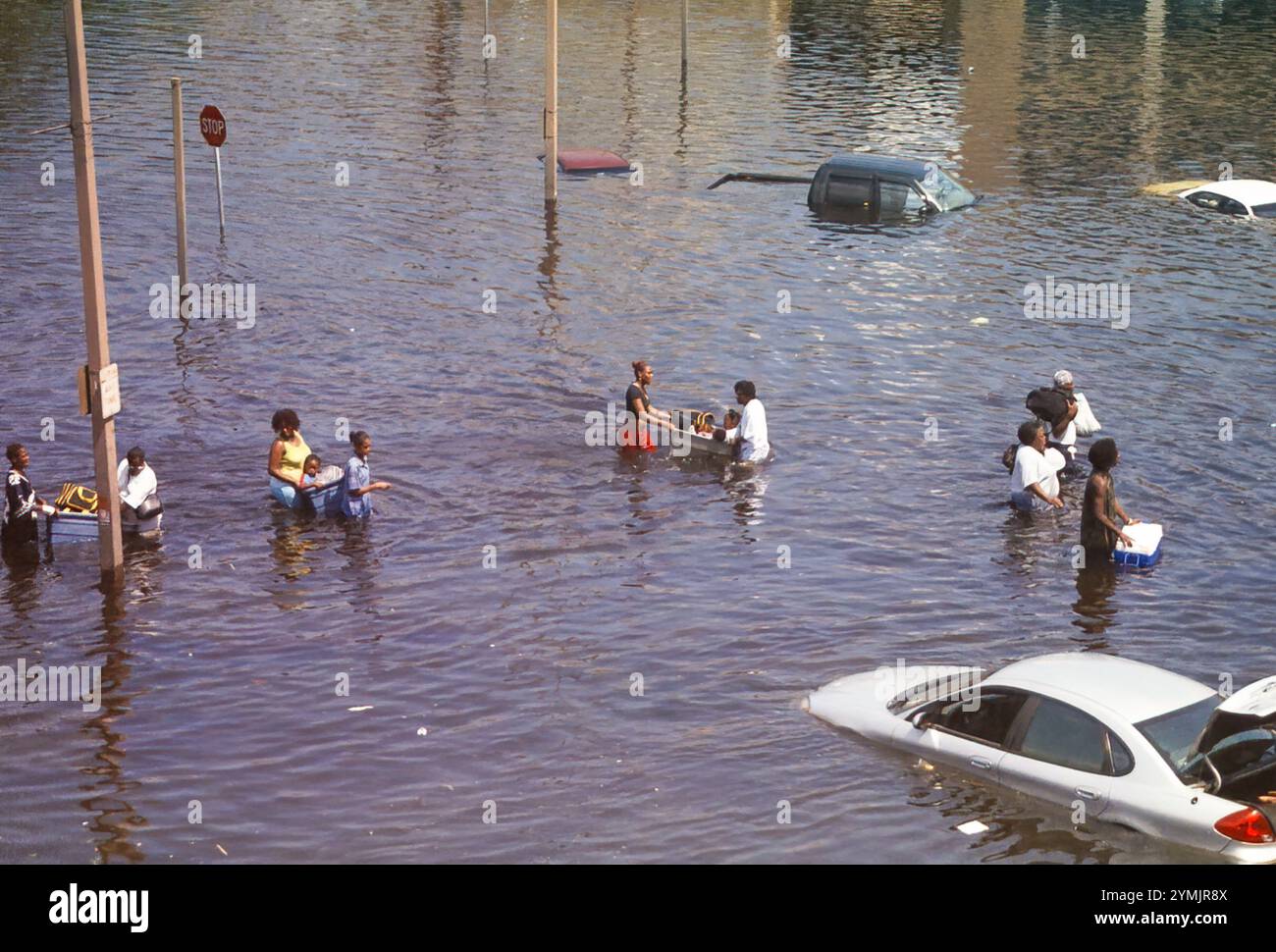 New Orleans, LOUISIANA, USA - agosto 2005: Strada allagata intorno al Superdome con persone che spostano i membri della famiglia in sicurezza dopo il fallimento dell'argine a seguito dell'uragano Katrina. La gente mette bambini e oggetti personali in vasche di plastica sulla strada per rifugiarsi al Superdome. La foto è stata scattata con una macchina fotografica da 35 mm del Superdome. Foto Stock