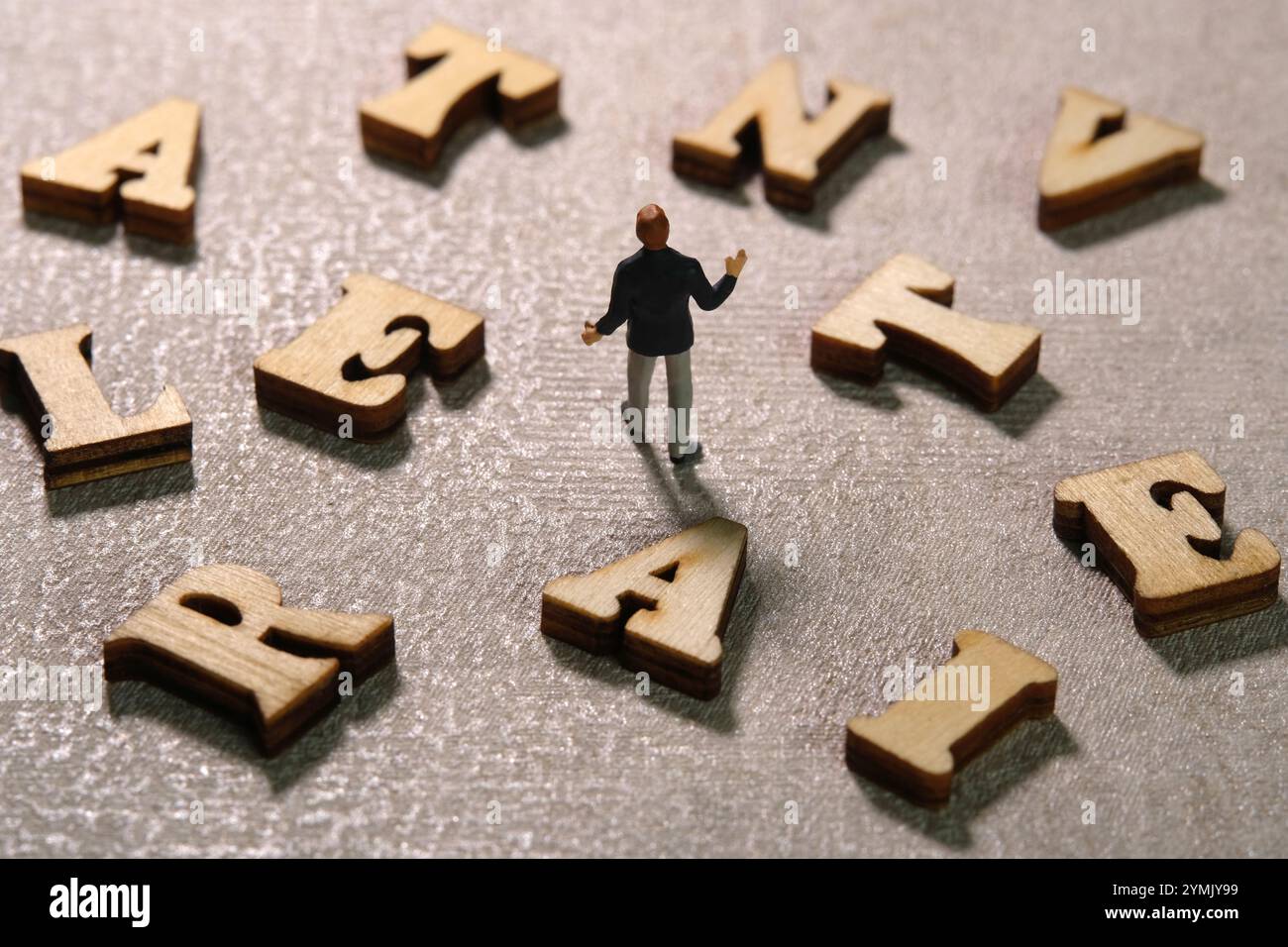 Fotografia di figure giocattolo per persone in miniatura. Vista posteriore uomo d'affari in mezzo all'alfabeto ALTERNATIVO. Foto immagine Foto Stock