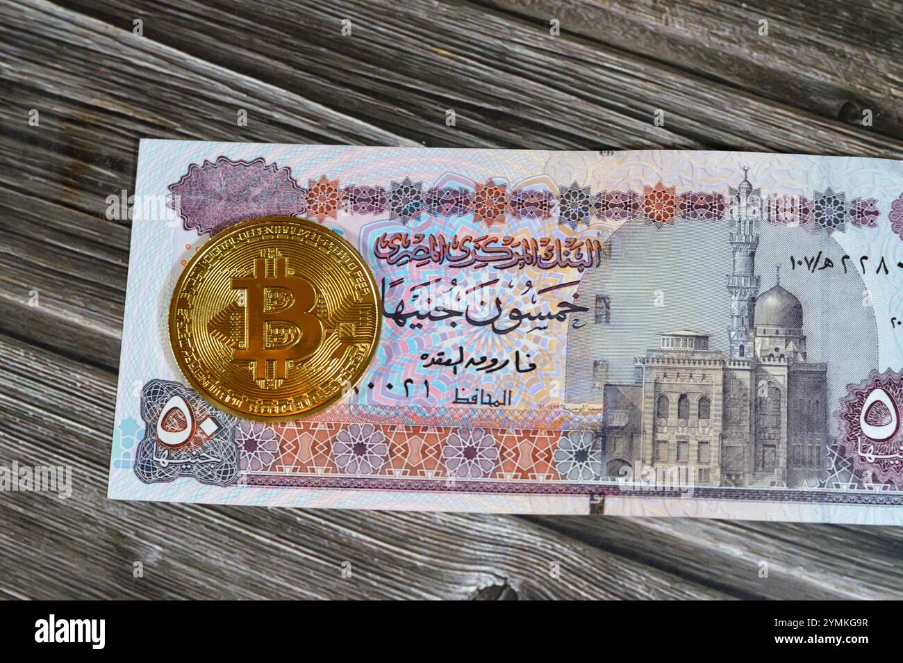 Banconota in sterline egiziane con moneta d'oro fisica Bitcoin, BTC la prima criptovaluta decentralizzata, nodi in rete bitcoin P2P verificano la transa Foto Stock