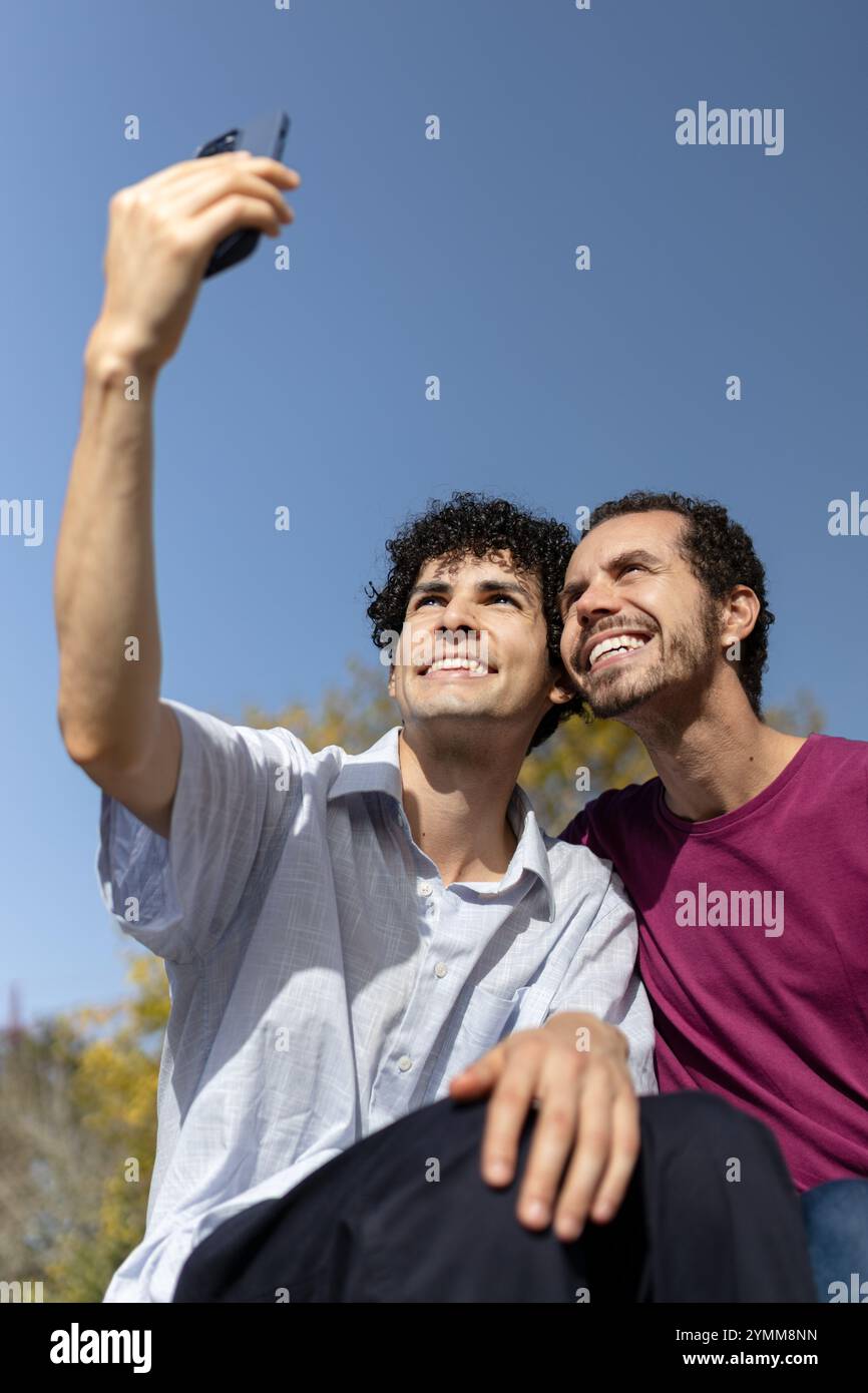 Due uomini che fanno un selfie in una giornata di sole, si godono il tempo insieme. Copia spazio Foto Stock