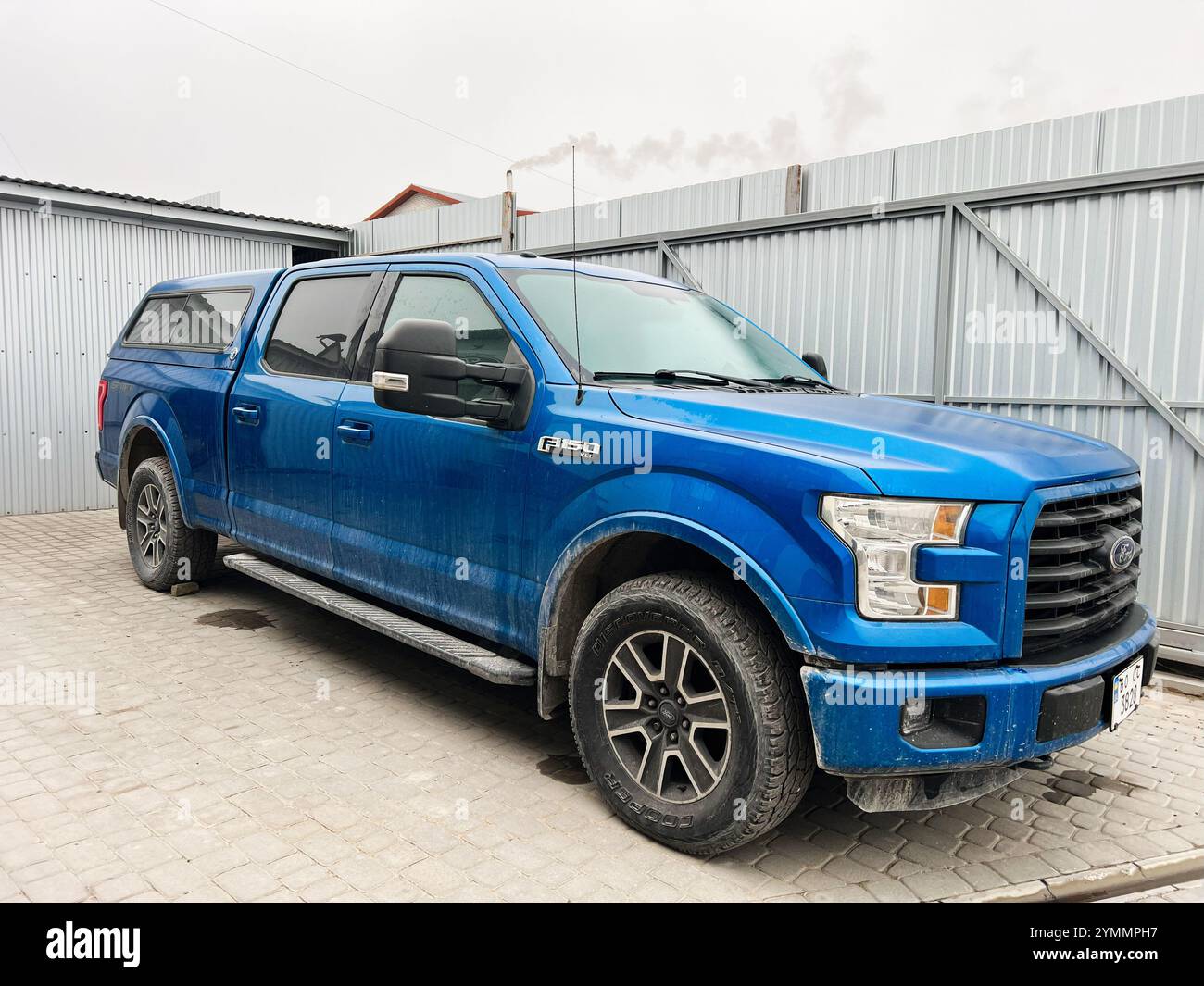 Kiev, Ucraina - 22 novembre 2024: Pick-up blu Ford F 150 con cabina estesa parcheggiata su una superficie pavimentata accanto a una recinzione metallica. Ideale per un Foto Stock