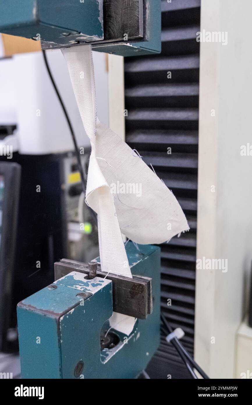 In vista ravvicinata, il test di resistenza allo strappo di un tessuto in una fabbrica tessile o in un laboratorio di ricerca e sviluppo. Foto Stock