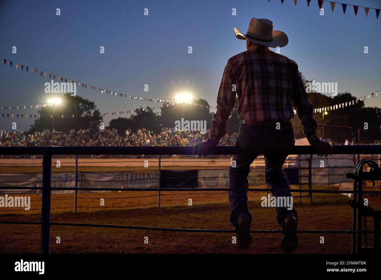 Cowboy seduto su una ferrovia a guardare il rodeo Foto Stock