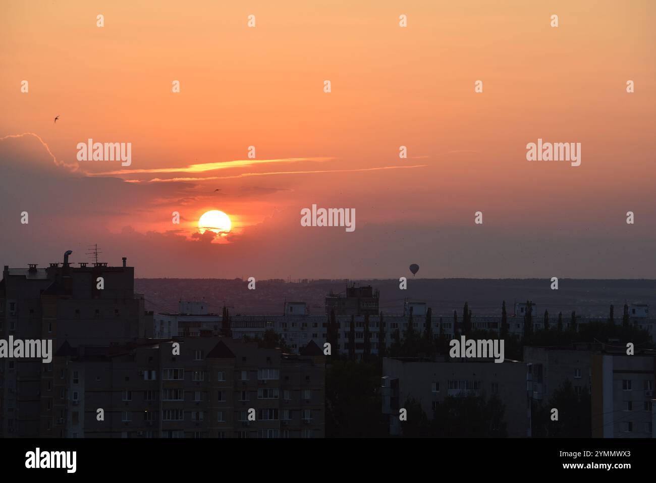 Incredibile tramonto su un paesaggio urbano con una mongolfiera Foto Stock