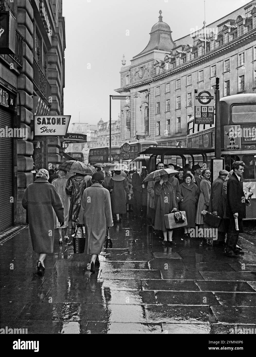 I passeggeri attendono sotto la pioggia gli autobus durante l'ora di punta a Regent Street, intorno agli anni '1960 Foto Stock