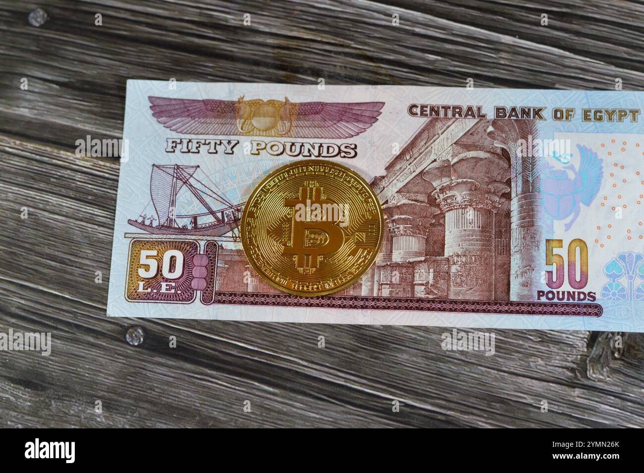 Banconota in sterline egiziane con moneta d'oro fisica Bitcoin, BTC la prima criptovaluta decentralizzata, nodi in rete bitcoin P2P verificano la transa Foto Stock