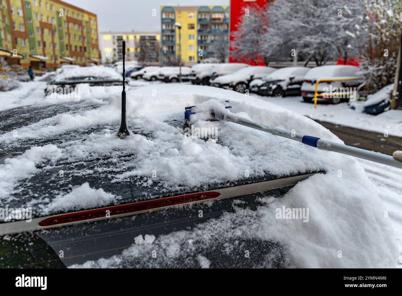 Una donna spara la neve dalla macchina, rimuovendo il ghiaccio dal corpo della macchina, attaccando l'inverno, preparando la macchina per il percorso Foto Stock