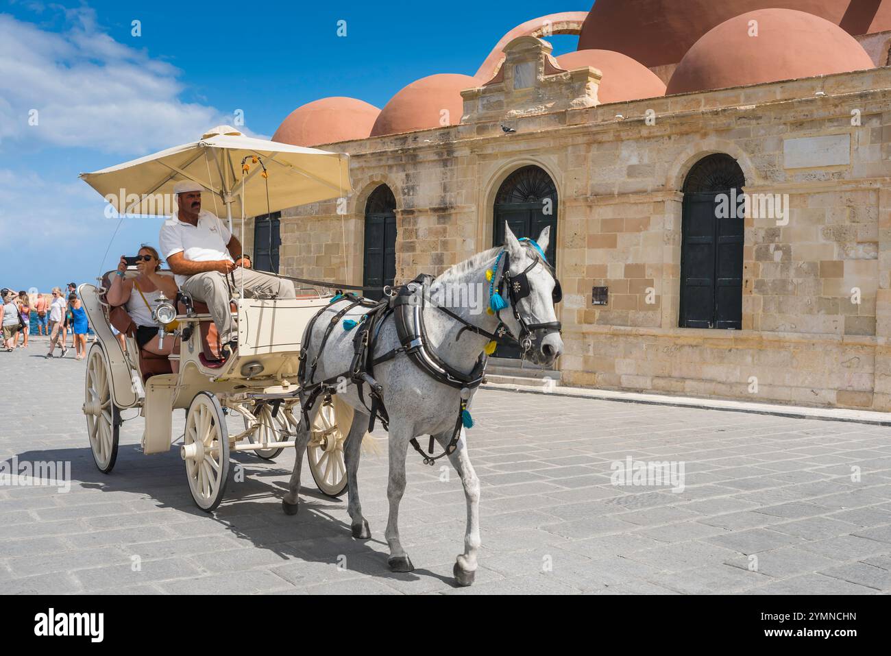 Turismo in Grecia, vista in estate di un turista su una carrozza trainata da cavalli che fa un tour della vecchia zona del porto veneziano a Chania (Hania), Creta, Grecia Foto Stock