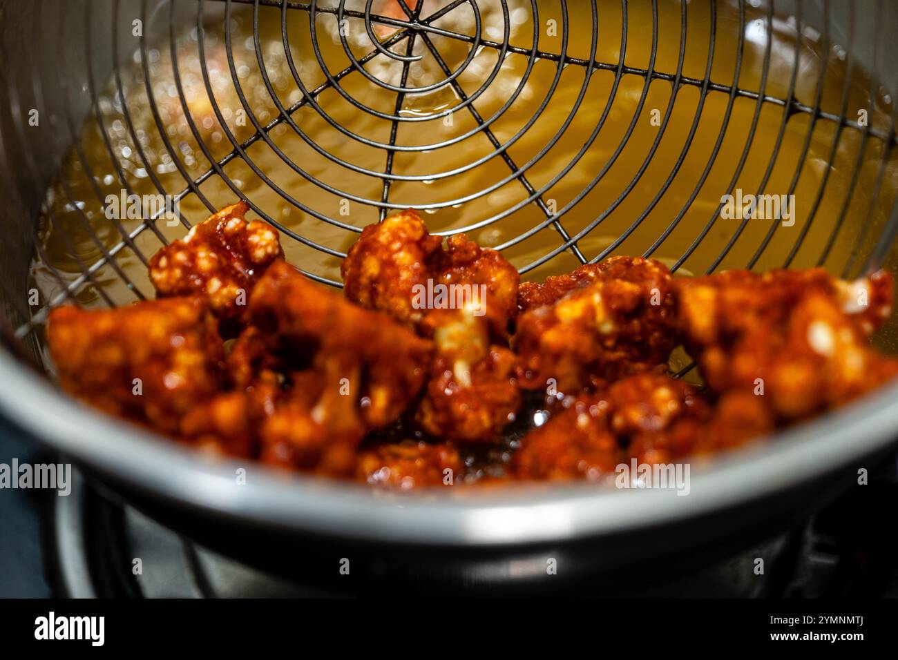 Fritture croccanti di cavolfiore in olio caldo, condite con spezie. Uno spuntino o un antipasto delizioso e salutare. Foto Stock