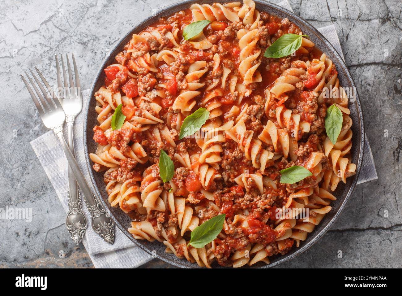 Pasta fusilli piccante con salsa di carne alla bolognese primo piano in un piatto sul tavolo. Vista dall'alto orizzontale Foto Stock