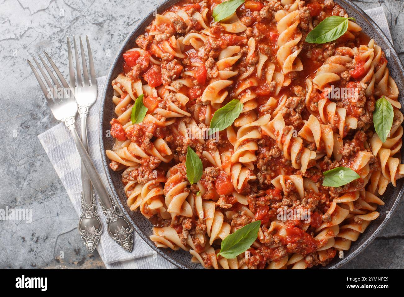 Pasta Fusilloni italiana con carne macinata, salsa di pomodoro e primi piani di verdure sul piatto del tavolo. Vista dall'alto orizzontale Foto Stock