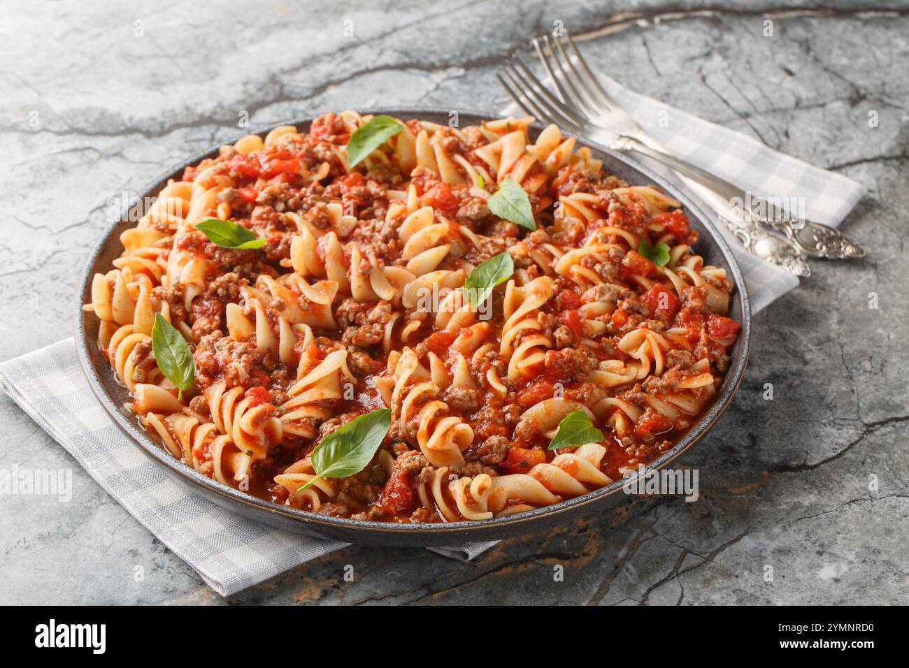 Pasta fusilli piccante con salsa di carne alla bolognese primo piano in un piatto sul tavolo. Orizzontale Foto Stock