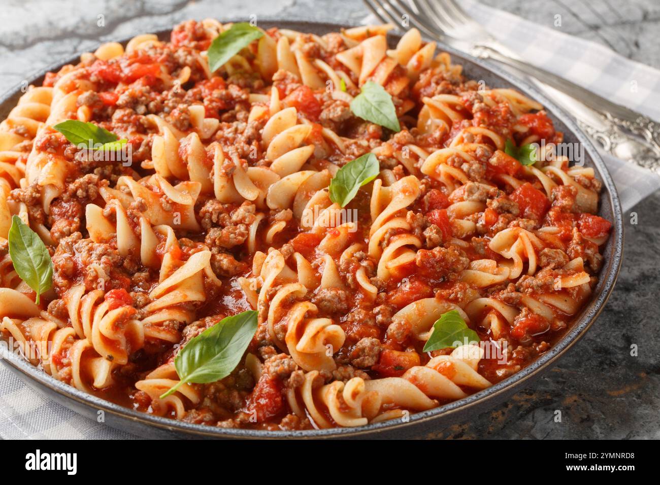 Pasta Fusilloni italiana con carne macinata, salsa di pomodoro e primi piani di verdure sul piatto del tavolo. Orizzontale Foto Stock