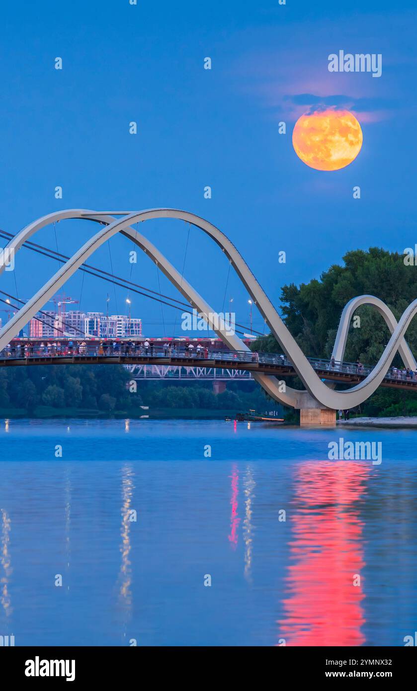 La gente guarda la Luna Buck sorgere sopra la città da un ponte pedonale, Kiev, Ucraina. Foto Stock