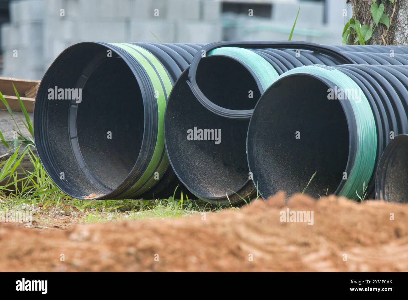 Tre tubi neri con maniglie verdi sono seduti a terra. I tubi sono realizzati in plastica e sono di colore nero e verde. Sono organizzati in un Foto Stock