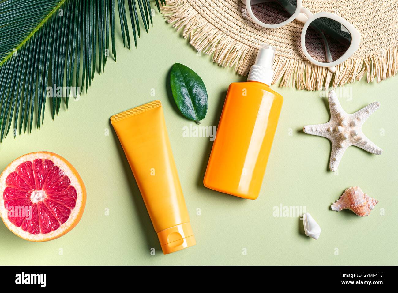 Vacanze estive, protezione UV. Crema solare arancione, occhiali da sole, cappello di paglia, stelle marine e foglie di palma su sfondo verde. Protezione solare SPF c Foto Stock