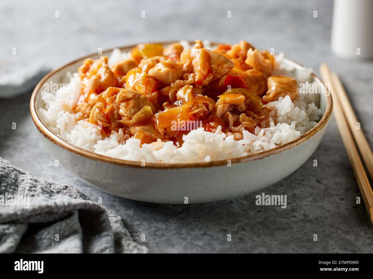ciotola di riso bollito con salsa agrodolce di pollo sul tavolo da cucina grigio Foto Stock