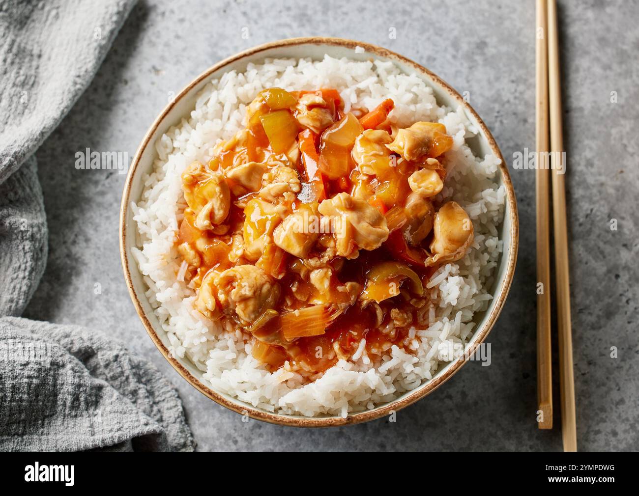 ciotola di riso bollito con salsa agrodolce di pollo sul tavolo da cucina grigio Foto Stock