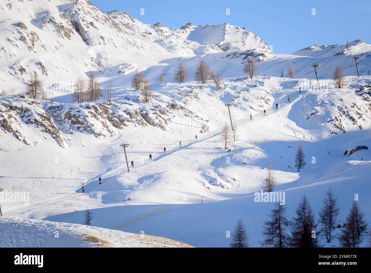 Sciatori che cavalcano uno skilift in una stazione sciistica delle Alpi in una giornata invernale limpida Foto Stock