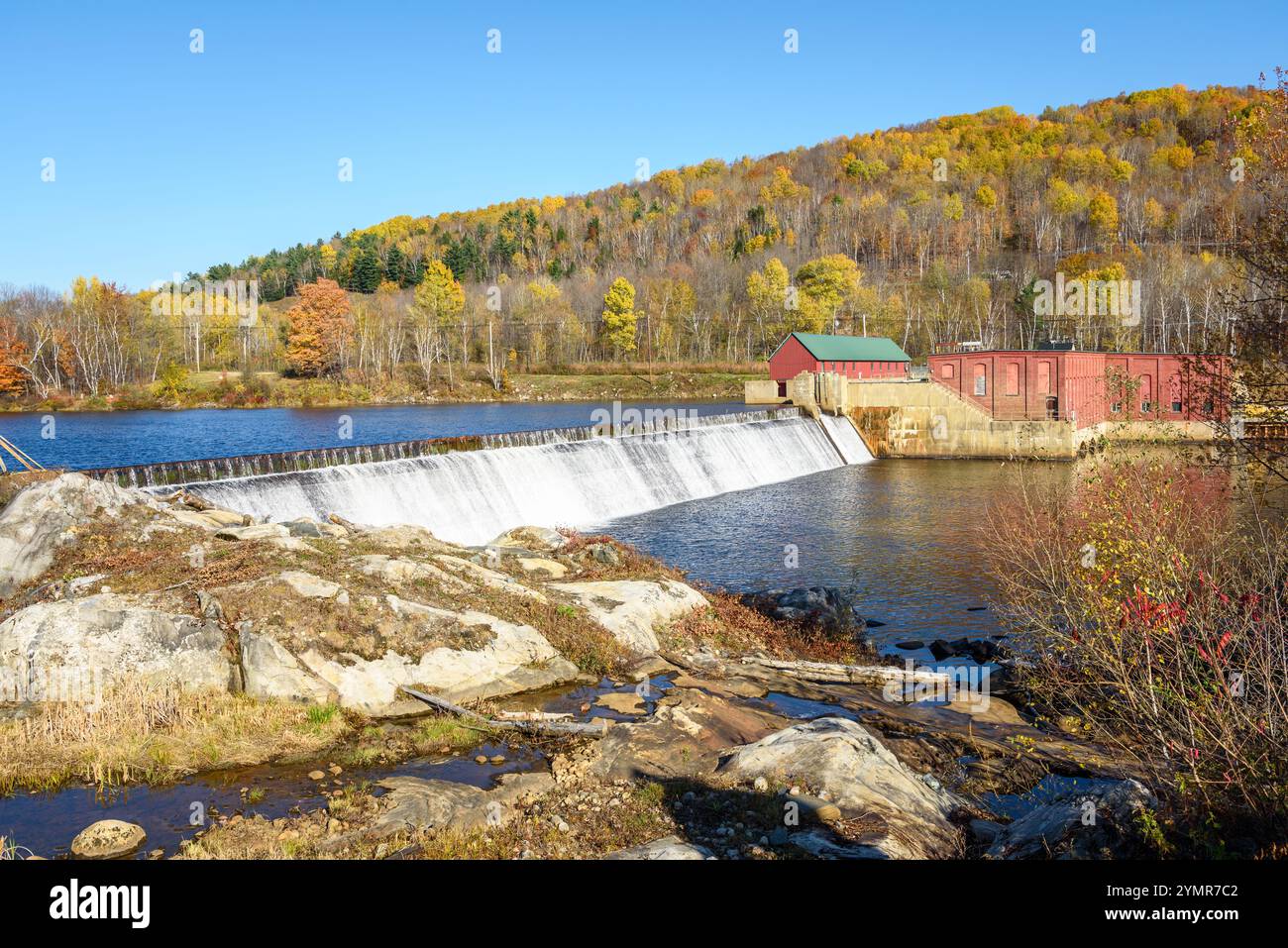 Piccola centrale idroelettrica lungo un fiume di montagna in una limpida giornata autunnale Foto Stock
