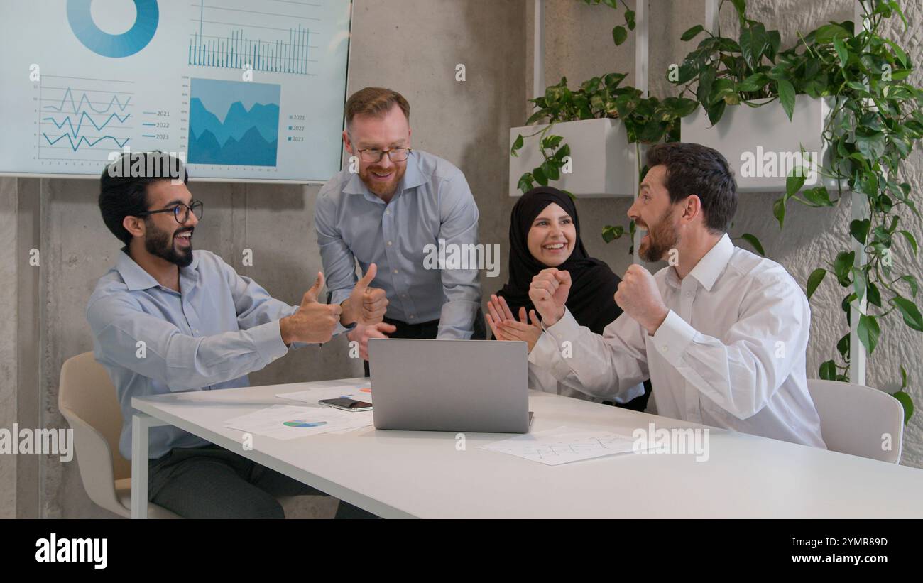 Persone d'affari diverse e felici il gruppo di team multirazziale celebra il successo della crescita delle vendite su notebook uomini d'affari e donne d'affari entusiasti ottengono un lavoro di squadra unitario Foto Stock