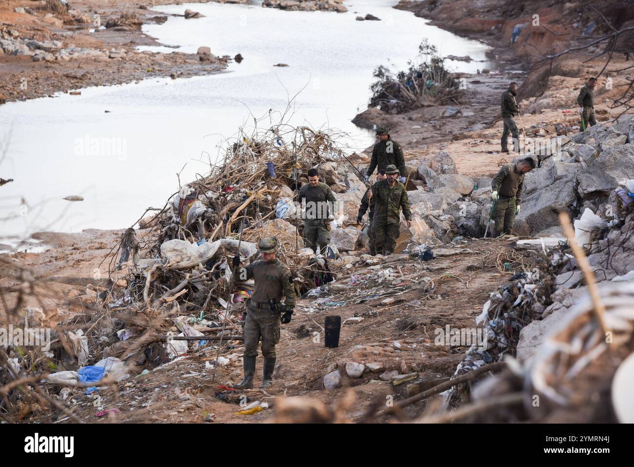 Torrente, Spagna - 22 novembre 2024. Membri del corpo militare spagnolo che tracciano il terreno camminando sul campo alla ricerca delle 8 persone ancora scomparse a Torrente. L'area è la gola Horteta (Barranco Horteta) nel quartiere Xenillet, la zona più colpita della città, dove sono stati ritrovati più di un cadavere dopo il disastro del 29 ottobre. Il ponte pedonale per accedere alla scuola pubblica CEIP Juan XXIII è stato distrutto dal flusso d'acqua e dalla rete elettrica danneggiate e ora è stato lentamente riparato dai tecnici delle linee elettriche. Crediti: Roberto Arosio/Alamy Live News. Foto Stock