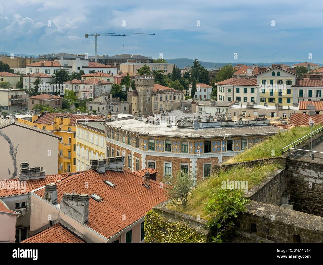 Trieste, Italia - 27 giugno 2024: Storico castello di San giusto. Paesaggio urbano affacciato sui bastioni se il complesso di appartamenti la Capitaine, affitti brevi, Foto Stock