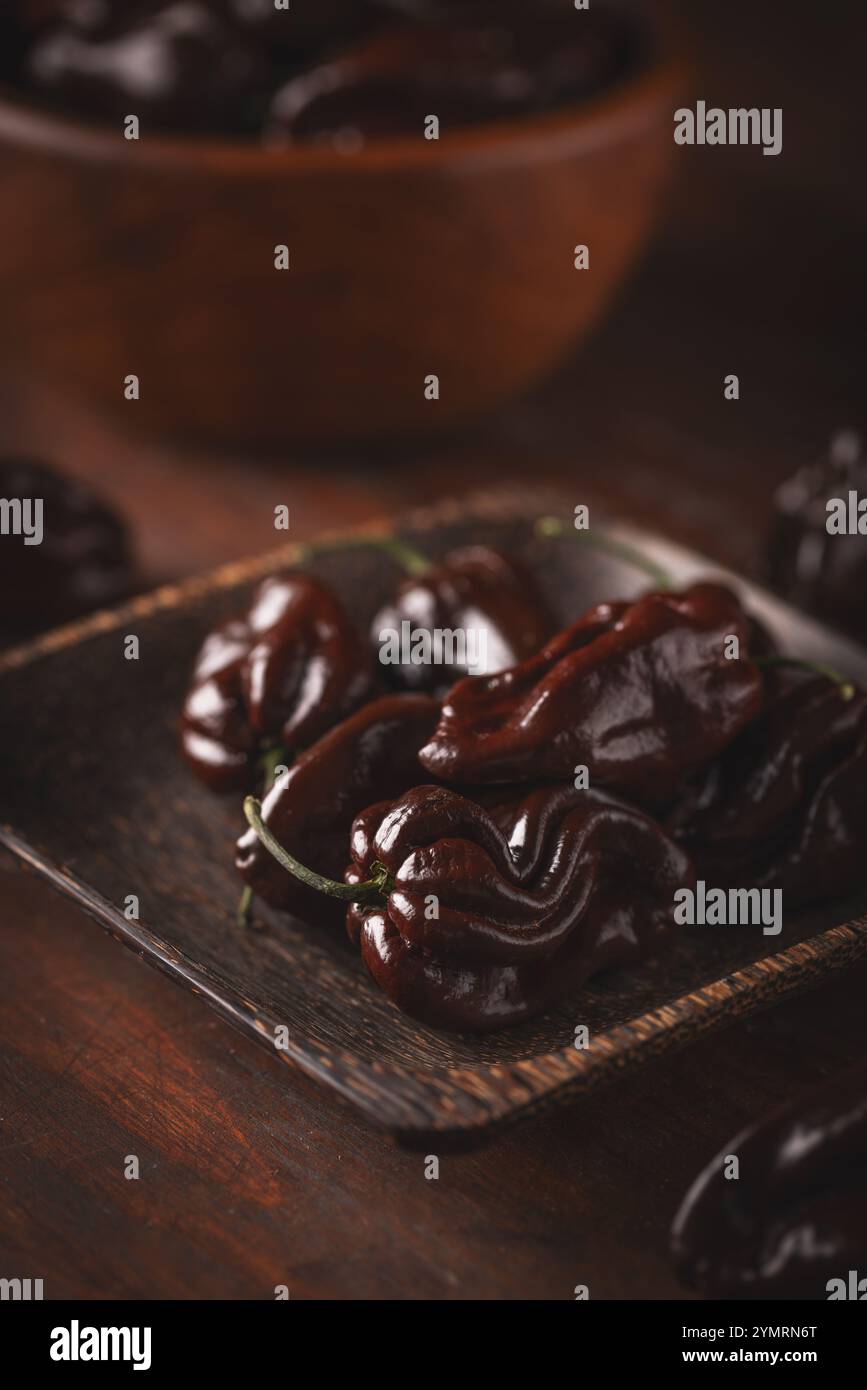 Peperoni habanero al cioccolato su vassoio di legno, delizia culinaria piccante Foto Stock
