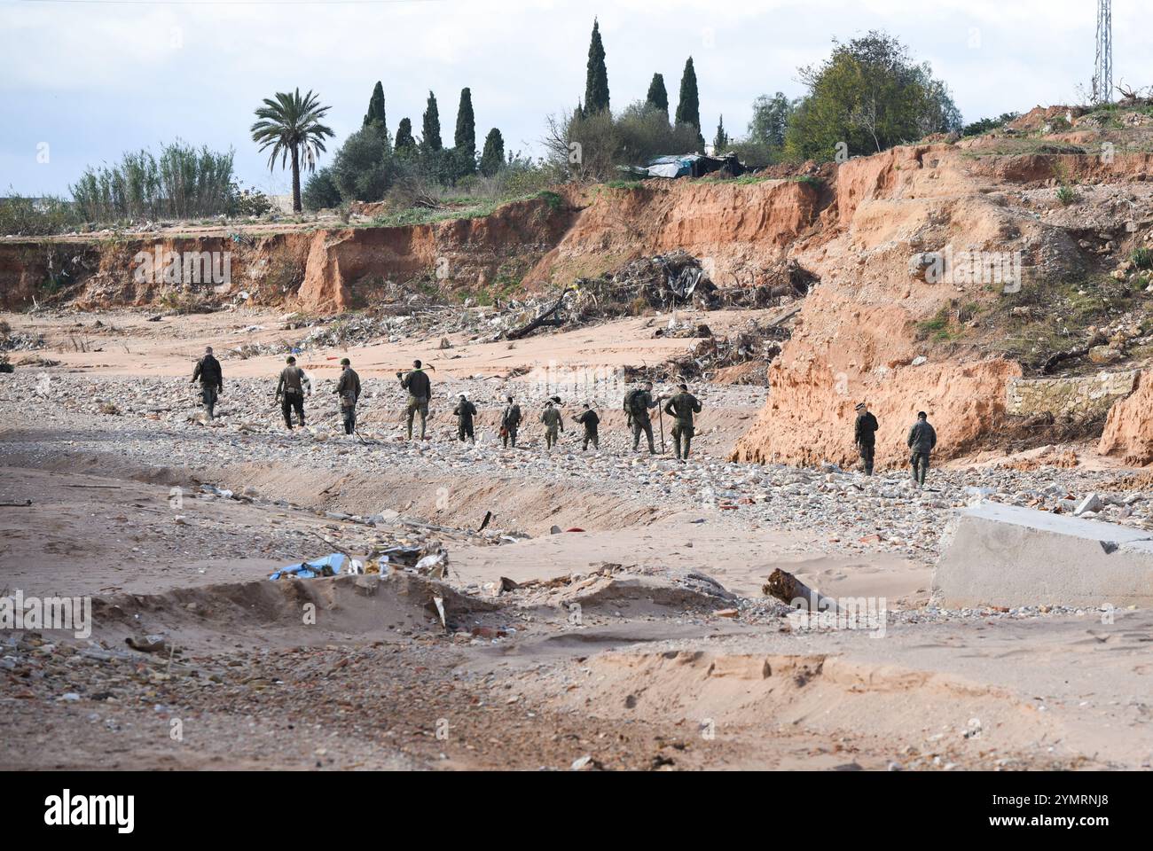 Torrente, Spagna - 22 novembre 2024. Membri del corpo militare spagnolo che tracciano il terreno camminando sul campo alla ricerca delle 8 persone ancora scomparse a Torrente. L'area è la gola Horteta (Barranco Horteta) nel quartiere Xenillet, la zona più colpita della città, dove sono stati ritrovati più di un cadavere dopo il disastro del 29 ottobre. Il ponte pedonale per accedere alla scuola pubblica CEIP Juan XXIII è stato distrutto dal flusso d'acqua e dalla rete elettrica danneggiate e ora è stato lentamente riparato dai tecnici delle linee elettriche. Crediti: Roberto Arosio/Alamy Live News. Foto Stock