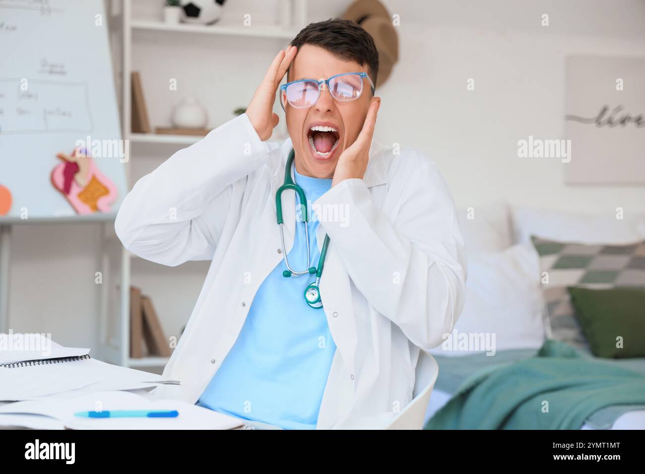 Studente di medicina maschile stressato in occhiali da vista a casa Foto Stock