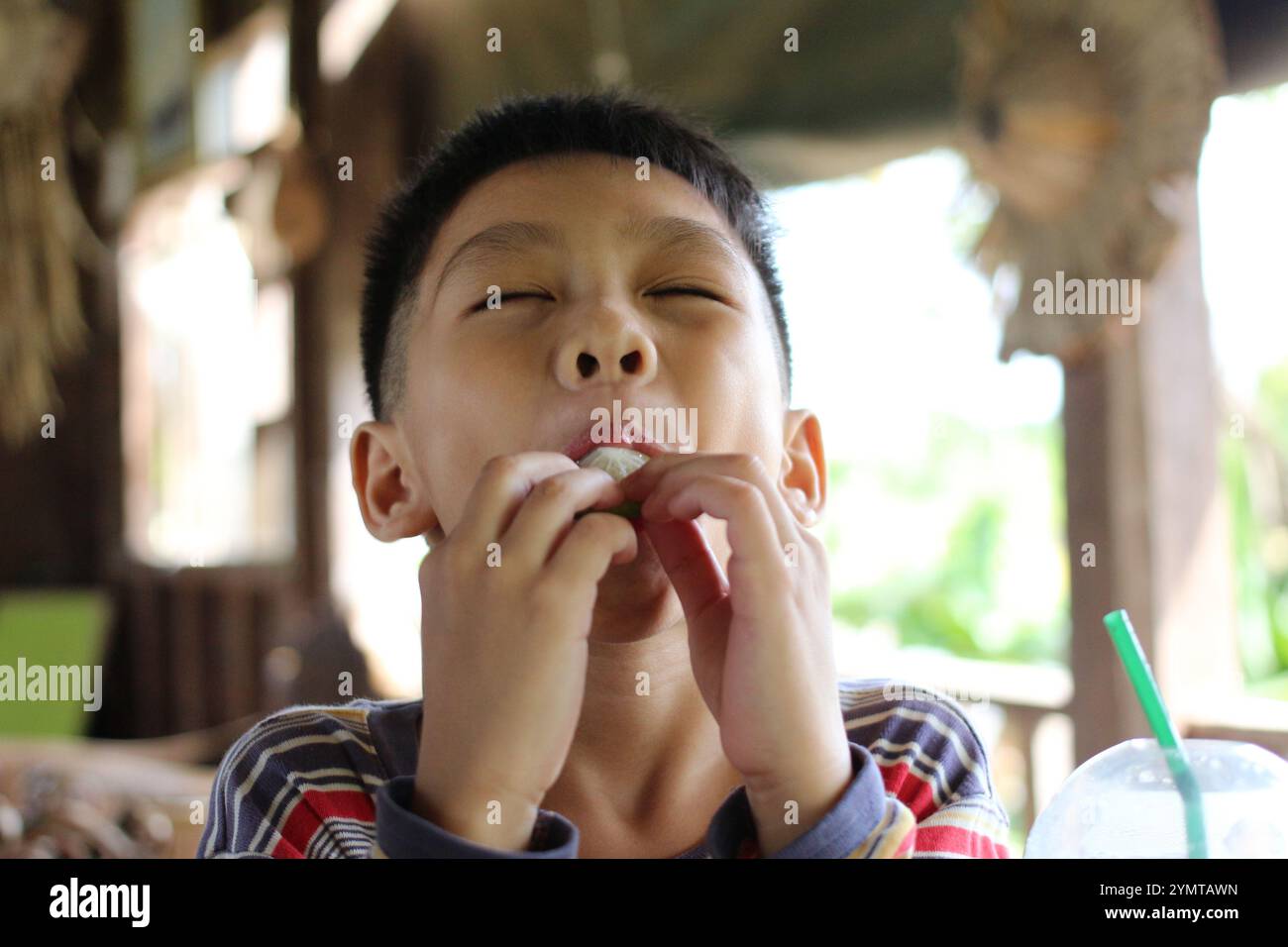 Un bambino gioioso si diverte con uno spuntino gustoso all'aperto, mostrando una vera espressione di felicità. Il momento spensierato cattura l'essenza della giovinezza e. Foto Stock