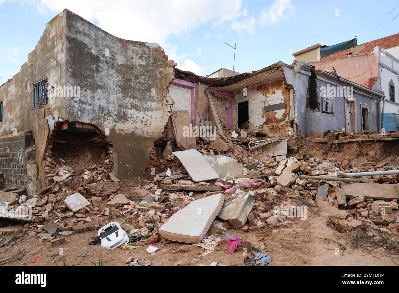 Torrente, Spagna - 22 novembre 2024. Abitanti zingari del quartiere Xenillet, la zona più colpita di Torrente durante le inondazioni DANA. Vivono a parte il letto del fiume e una di loro, una donna, ha perso la sua casa, la prima proprio sul bordo del burrone. Suo figlio sta guardando il paesaggio desolato. Si tratta di un gruppo di giovani ragazzi durante le operazioni di pulizia, aiutati da salvati per Servire, un'associazione evangeliana accreditata dalla protezione civile Italiana. Prevenire il collasso strutturale e distruggere case. Crediti: Roberto Arosio/Alamy Live News Foto Stock