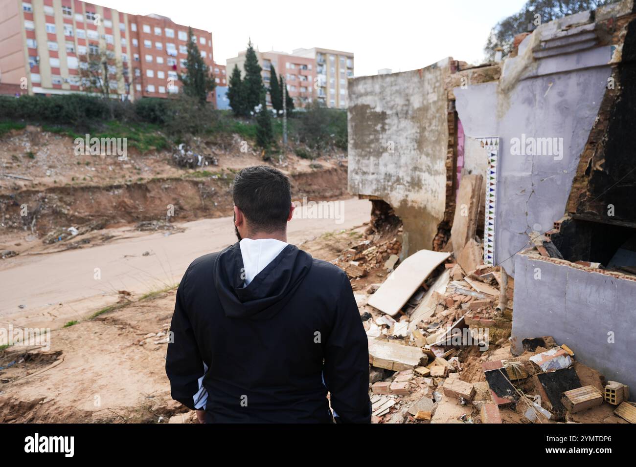Torrente, Spagna - 22 novembre 2024. Abitanti zingari del quartiere Xenillet, la zona più colpita di Torrente durante le inondazioni DANA. Vivono a parte il letto del fiume e una di loro, una donna, ha perso la sua casa, la prima proprio sul bordo del burrone. Suo figlio sta guardando il paesaggio desolato. Si tratta di un gruppo di giovani ragazzi durante le operazioni di pulizia, aiutati da salvati per Servire, un'associazione evangeliana accreditata dalla protezione civile Italiana. Prevenire il collasso strutturale e distruggere case. Crediti: Roberto Arosio/Alamy Live News Foto Stock