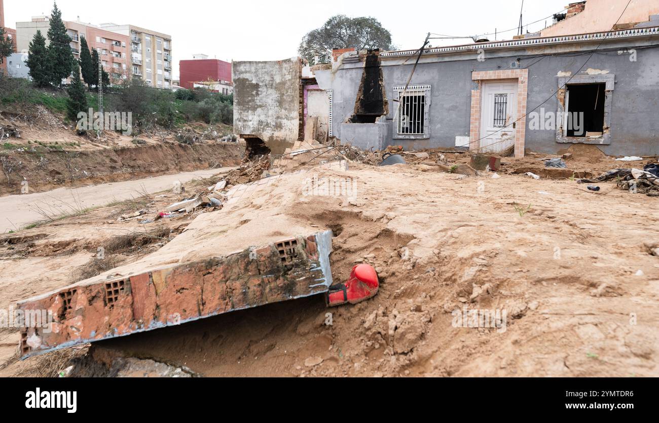 Torrente, Spagna - 22 novembre 2024. Abitanti zingari del quartiere Xenillet, la zona più colpita di Torrente durante le inondazioni DANA. Vivono a parte il letto del fiume e una di loro, una donna, ha perso la sua casa, la prima proprio sul bordo del burrone. Suo figlio sta guardando il paesaggio desolato. Si tratta di un gruppo di giovani ragazzi durante le operazioni di pulizia, aiutati da salvati per Servire, un'associazione evangeliana accreditata dalla protezione civile Italiana. Prevenire il collasso strutturale e distruggere case. Crediti: Roberto Arosio/Alamy Live News Foto Stock