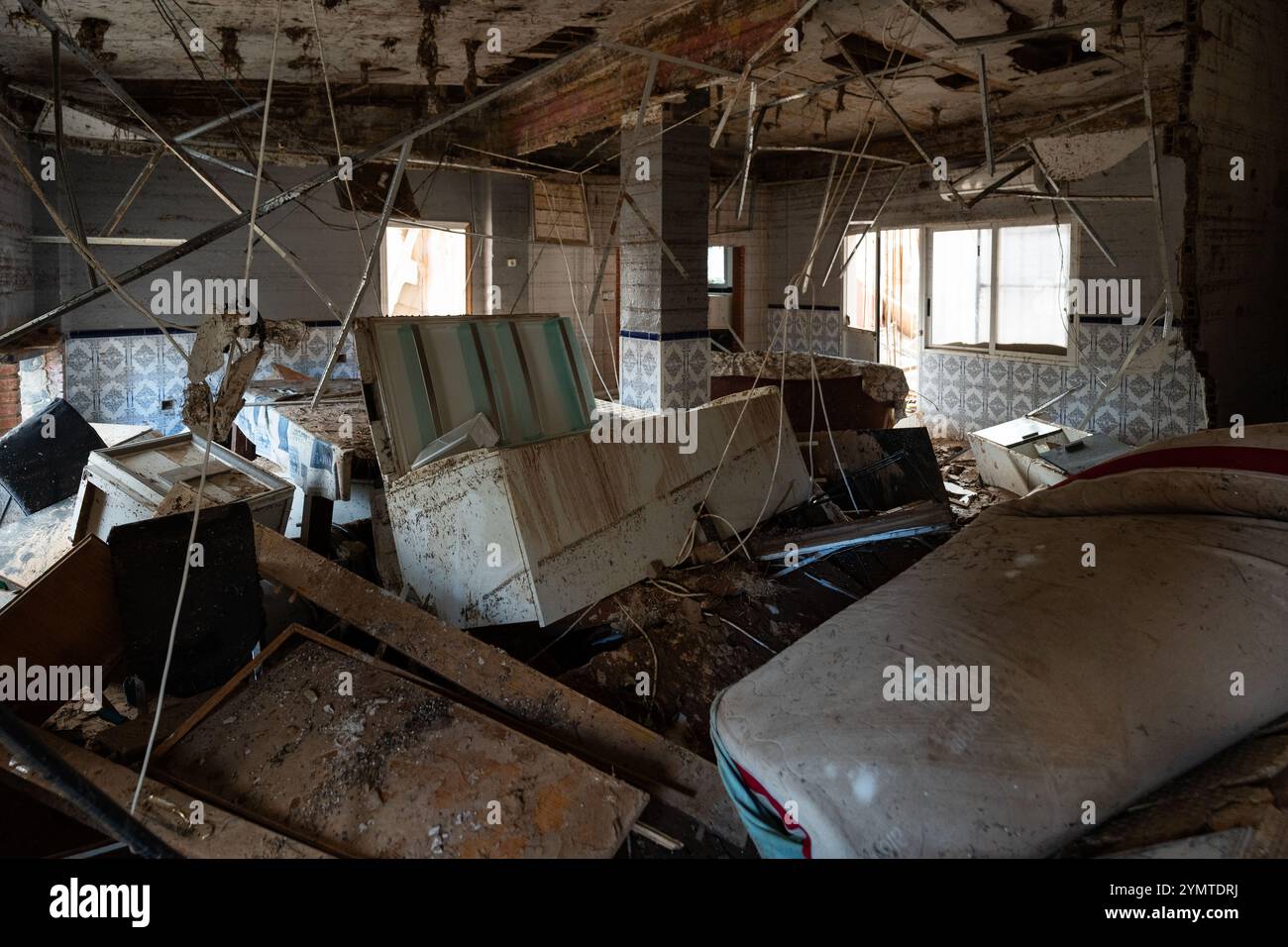 Torrente, Spagna - 22 novembre 2024. Abitanti zingari del quartiere Xenillet, la zona più colpita di Torrente durante le inondazioni DANA. Vivono a parte il letto del fiume e una di loro, una donna, ha perso la sua casa, la prima proprio sul bordo del burrone. Suo figlio sta guardando il paesaggio desolato. Si tratta di un gruppo di giovani ragazzi durante le operazioni di pulizia, aiutati da salvati per Servire, un'associazione evangeliana accreditata dalla protezione civile Italiana. Prevenire il collasso strutturale e distruggere case. Crediti: Roberto Arosio/Alamy Live News Foto Stock