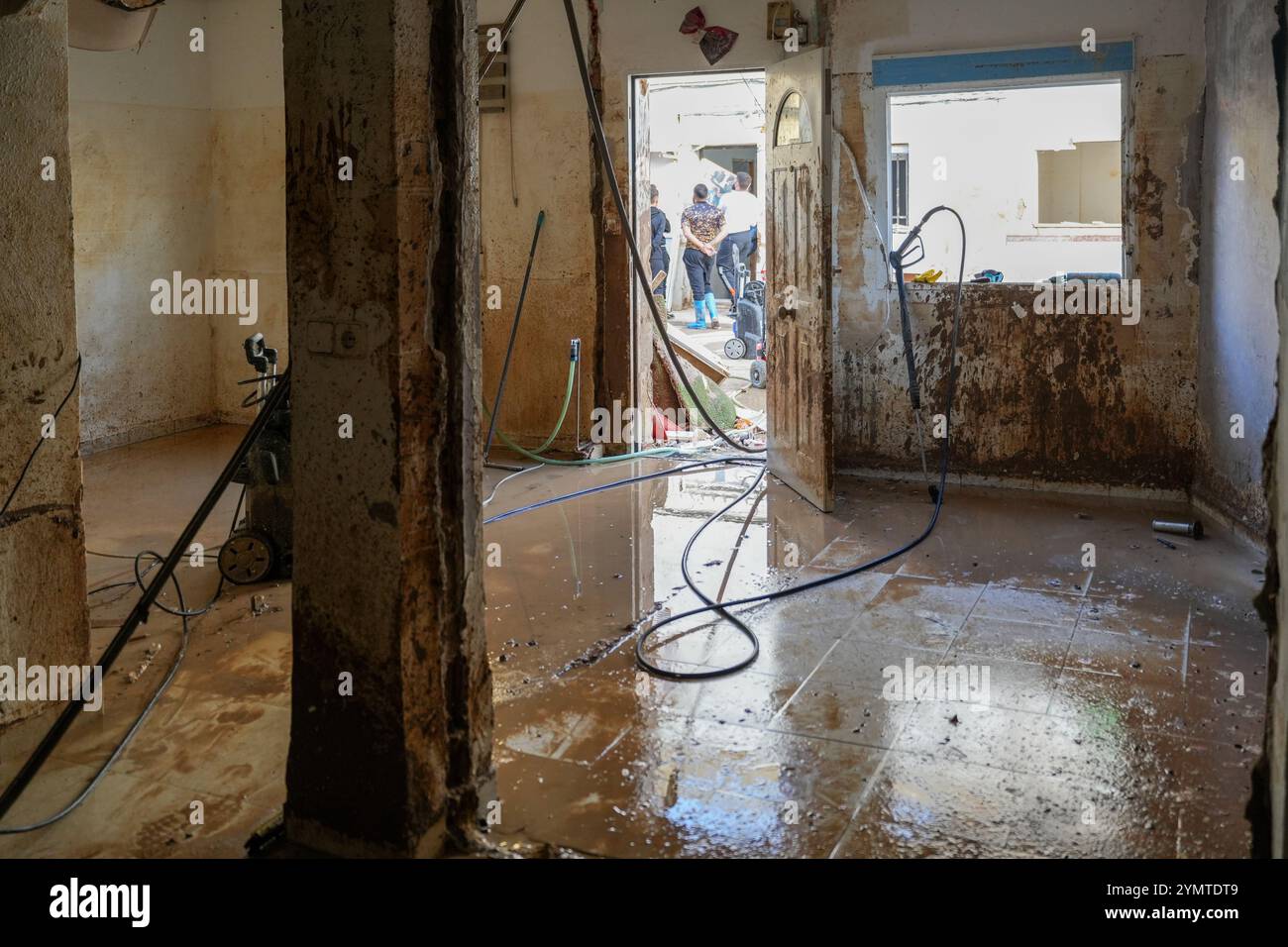 Torrente, Spagna - 22 novembre 2024. Abitanti zingari del quartiere Xenillet, la zona più colpita di Torrente durante le inondazioni DANA. Vivono a parte il letto del fiume e una di loro, una donna, ha perso la sua casa, la prima proprio sul bordo del burrone. Suo figlio sta guardando il paesaggio desolato. Si tratta di un gruppo di giovani ragazzi durante le operazioni di pulizia, aiutati da salvati per Servire, un'associazione evangeliana accreditata dalla protezione civile Italiana. Prevenire il collasso strutturale e distruggere case. Crediti: Roberto Arosio/Alamy Live News Foto Stock