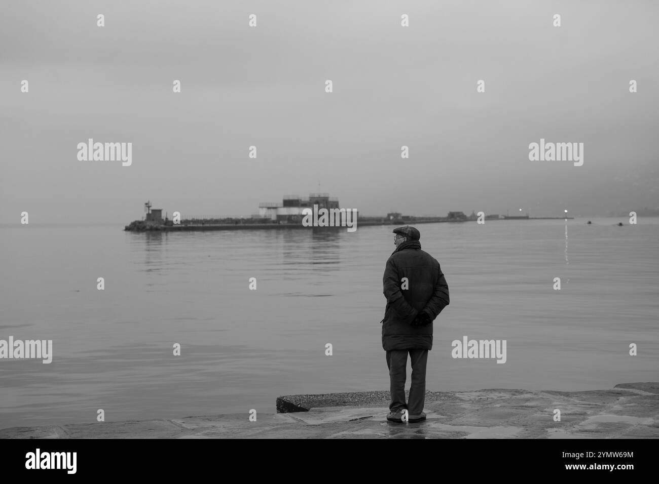 Uomo in piedi sul Molo audace la mattina presto. Trieste, Italia 03.01.2024 Foto Stock