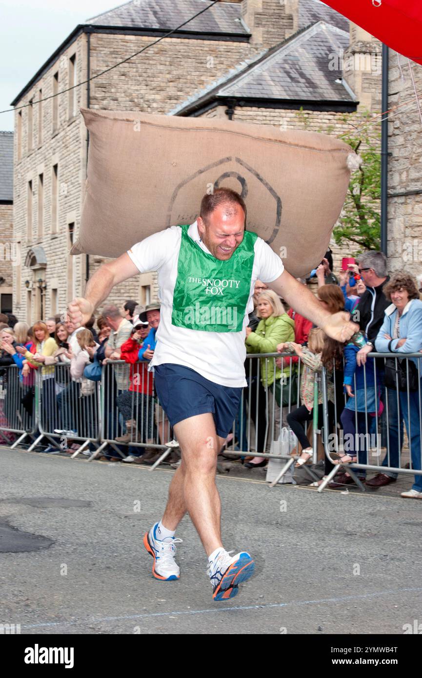Un uomo perde la presa del sacco di lana mentre attraversa la linea al Tetbury Woolsack May Bank Holiday Races nel Gloucestershire, Regno Unito. Foto Stock