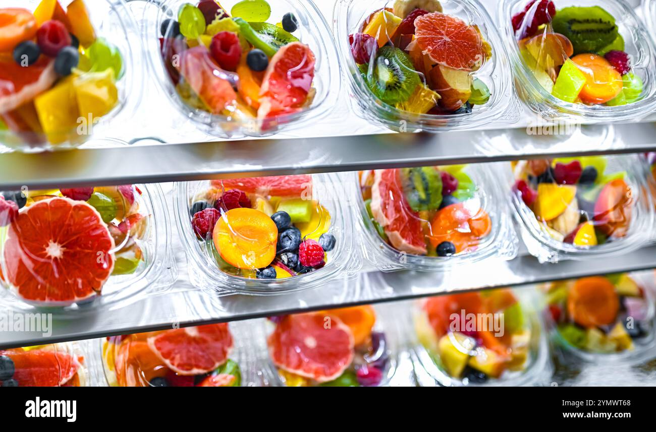 Scatole di plastica con macedonie di frutta preconfezionate, messe in vendita in un frigorifero commerciale Foto Stock