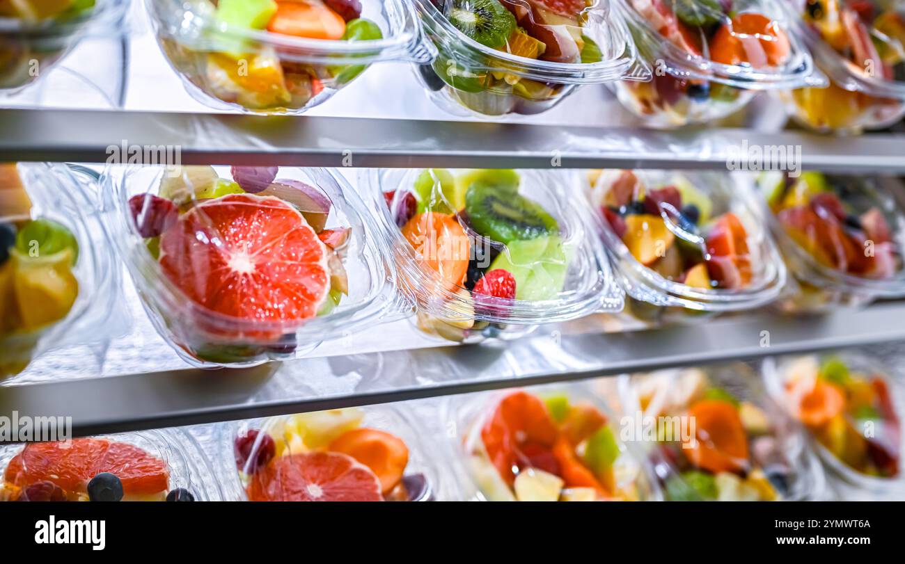 Scatole di plastica con macedonie di frutta preconfezionate, messe in vendita in un frigorifero commerciale Foto Stock