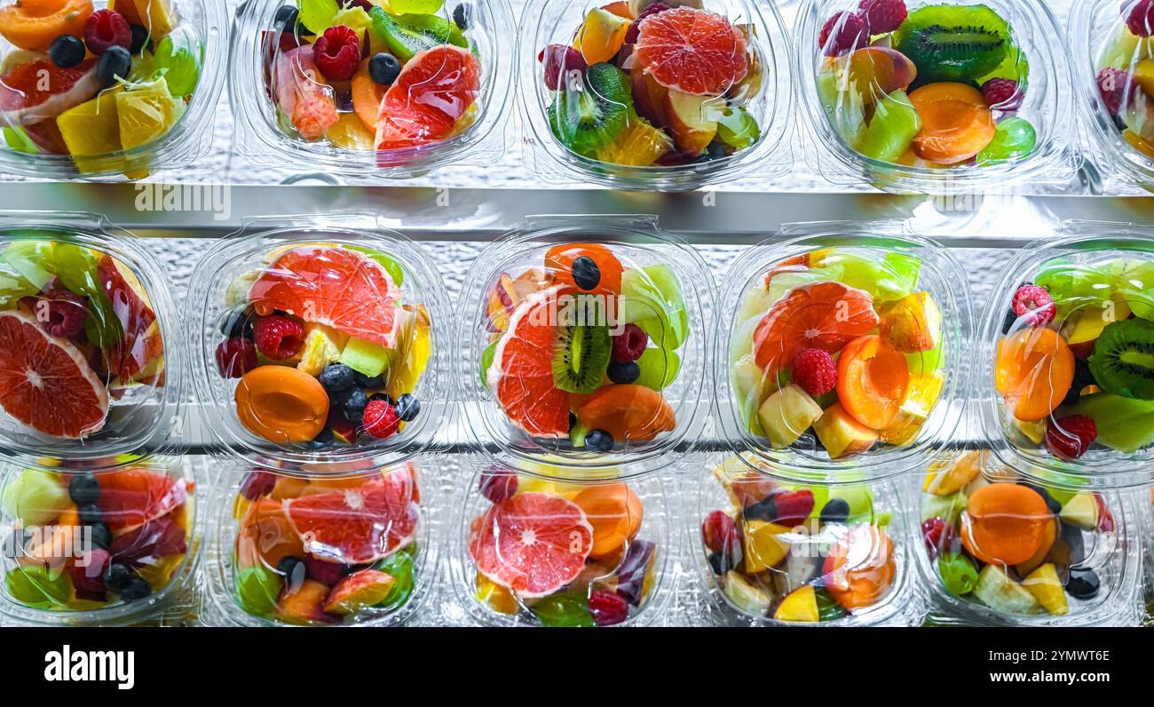 Scatole di plastica con macedonie di frutta preconfezionate, messe in vendita in un frigorifero commerciale Foto Stock