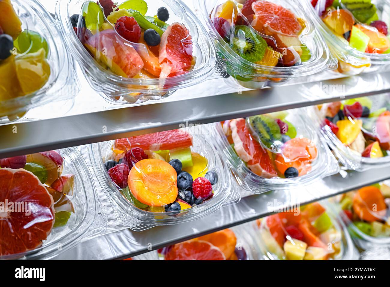 Scatole di plastica con macedonie di frutta preconfezionate, messe in vendita in un frigorifero commerciale Foto Stock