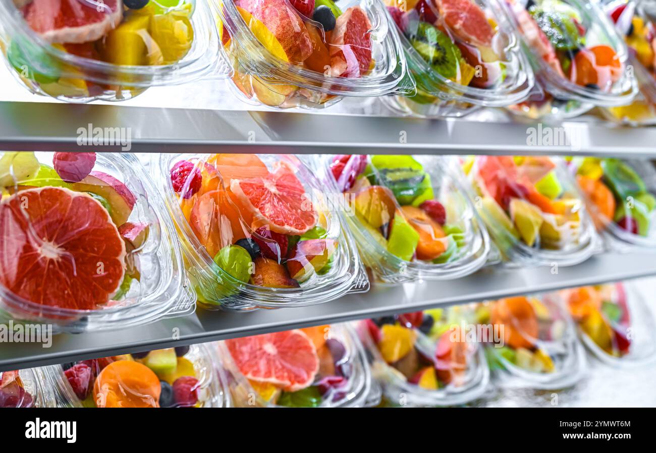 Scatole di plastica con macedonie di frutta preconfezionate, messe in vendita in un frigorifero commerciale Foto Stock
