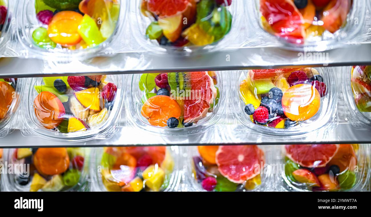 Scatole di plastica con macedonie di frutta preconfezionate, messe in vendita in un frigorifero commerciale Foto Stock