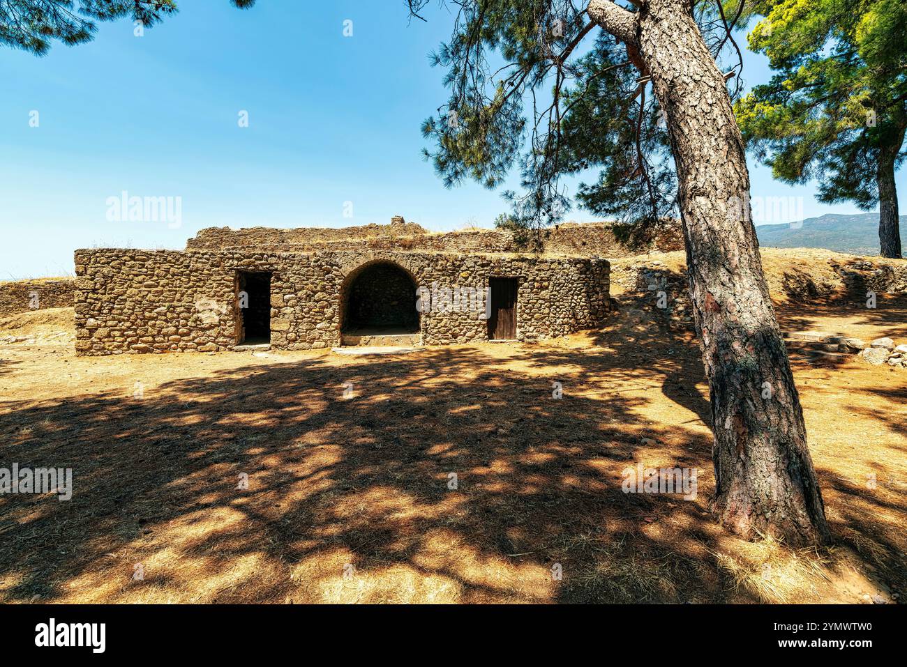 Un'antica struttura in pietra all'interno dei giardini del Castello di Kalamata, che mostra l'architettura medievale circondata da alberi e spazi aperti. Foto Stock