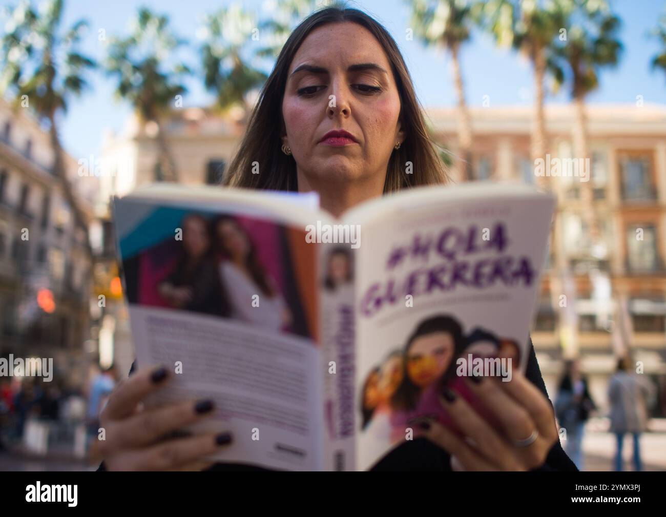 Malaga, Spagna. 23 novembre 2024. Un'attivista è vista guardare un libro mentre prende parte a una performance per celebrare la giornata internazionale per l'eliminazione della violenza contro le donne, in piazza Plaza de la Constitucion. Attivisti e volontari dell'organizzazione non governativa "Prodiversa" hanno partecipato a un'attività artistica e teatrale organizzata dall'artista e interprete Verónica Ruth Frías per denunciare la violenza di genere. Questa proposta artistica unisce arte e attivismo. Credito: SOPA Images Limited/Alamy Live News Foto Stock