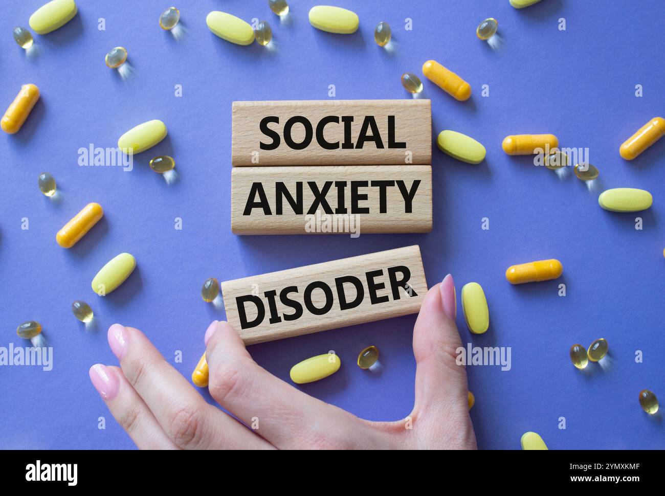 Simbolo del disturbo d'ansia sociale. Parole concettuali disturbo d'ansia sociale su blocchi di legno. Bellissimo sfondo viola con pillole. Mano del dottore. Healthcar Foto Stock