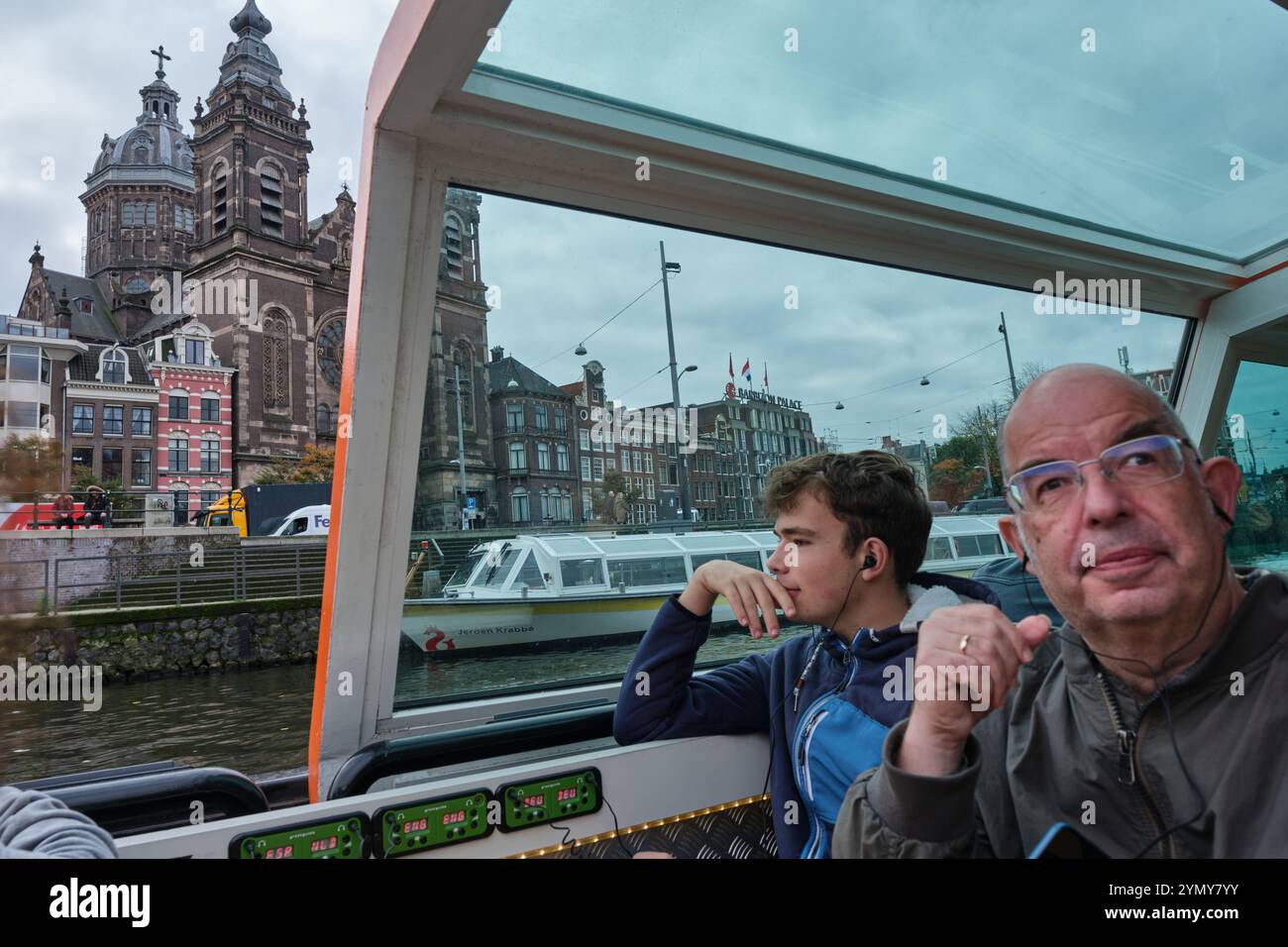 Turisti in un tour guidato dei canali del centro storico di Amsterdam. La Basilica di San Nicola è sullo sfondo, vicino alla stazione centrale Foto Stock